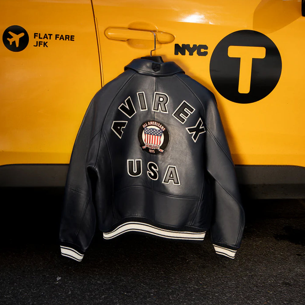Black leather jacket with 'AVIREX USA' branding in front of a yellow taxi.
