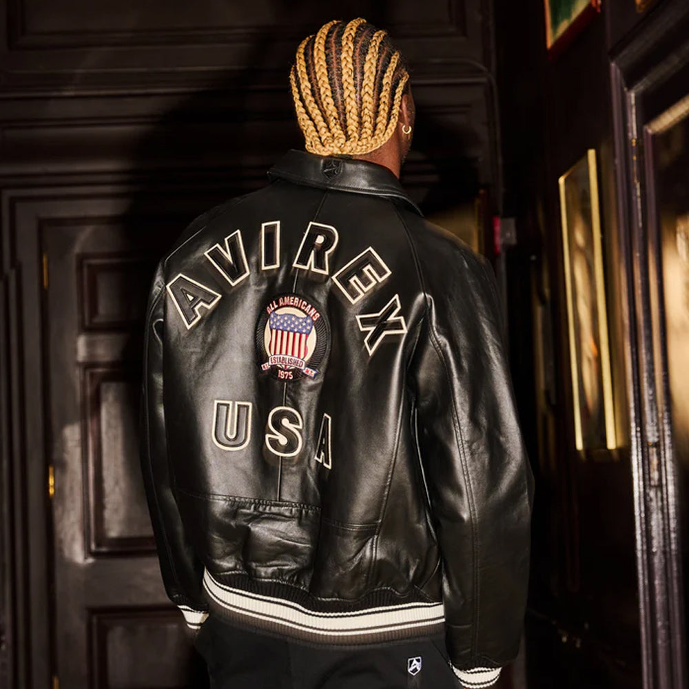 Person wearing a black leather jacket with 'AVIREX USA' branding in an indoor setting.