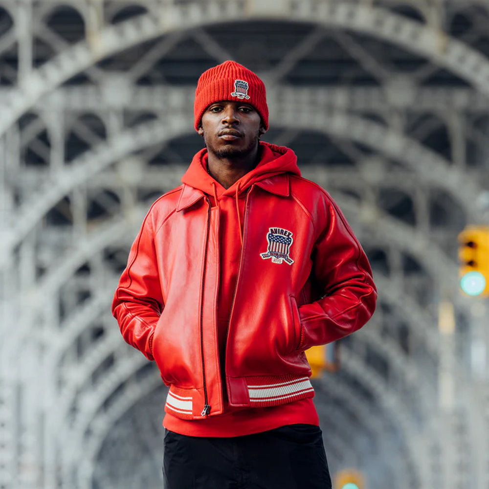 Person wearing a red jacket and beanie standing in front of a bridge