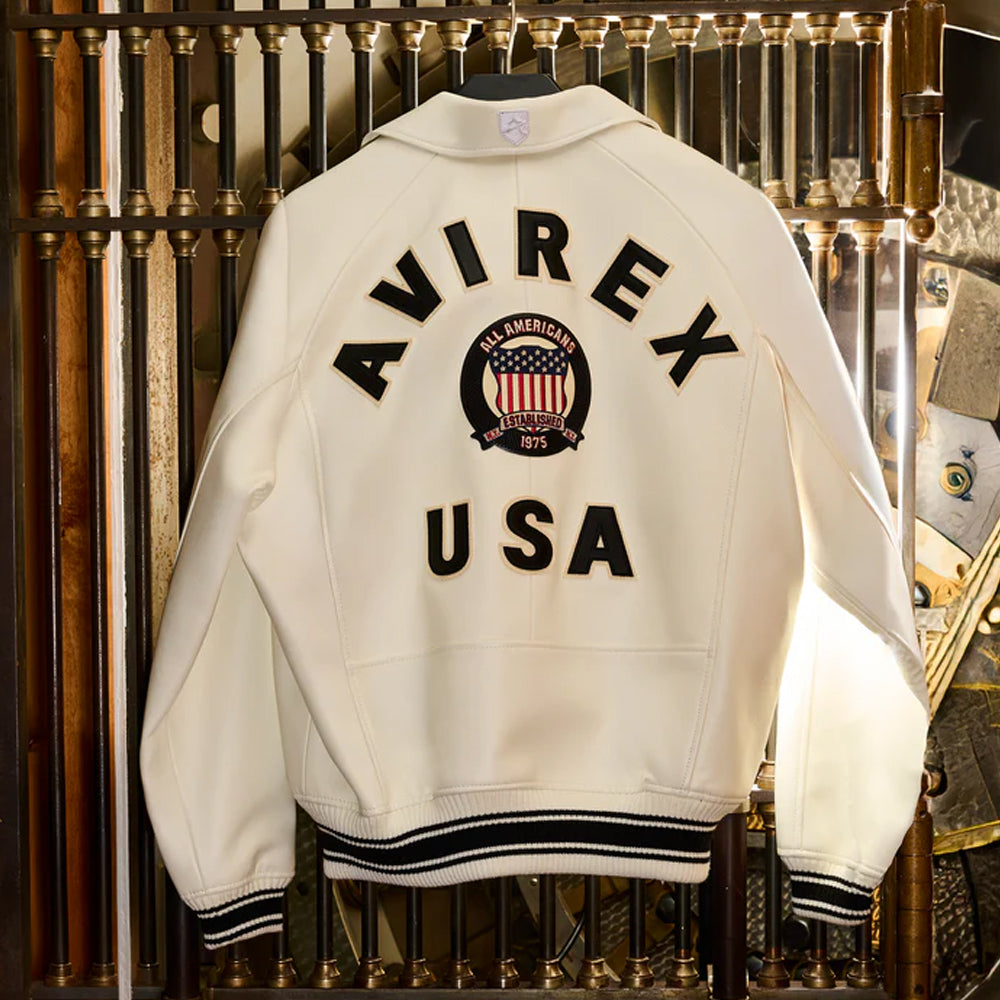 Person wearing a red 'AVIREX USA' jacket with another person in a black jacket, on a dark background.