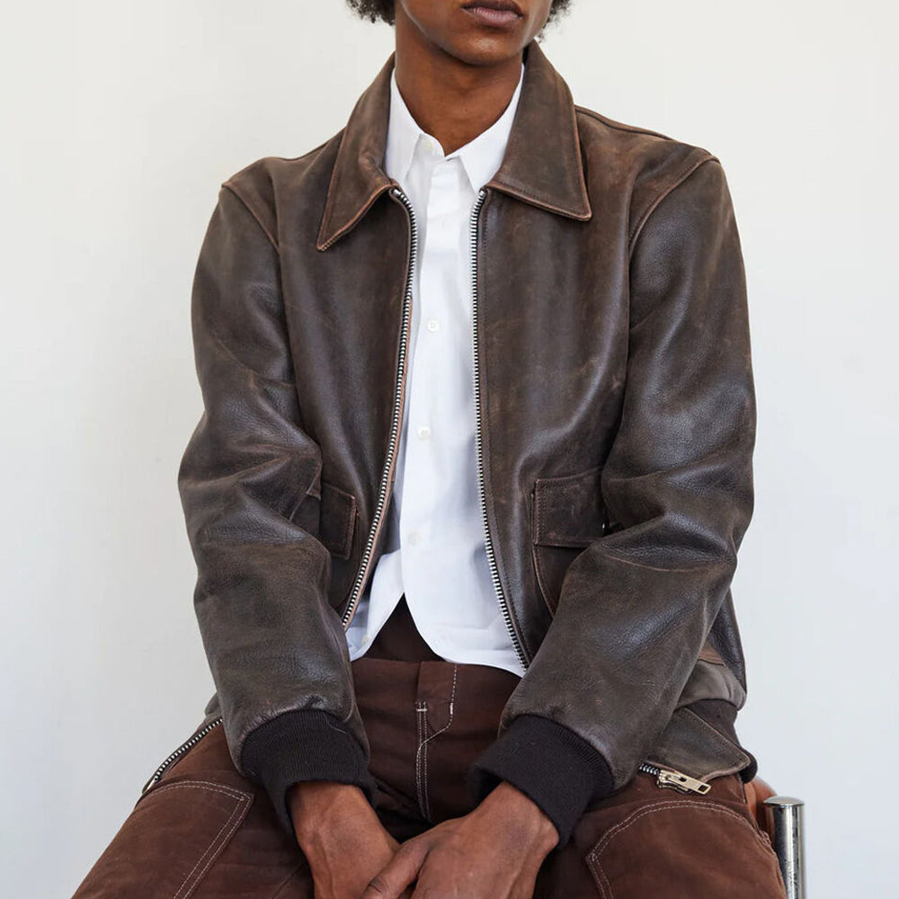 Man wearing the RAF Vintage A2 Brown Leather Bomber Jacket while sitting, emphasizing the timeless aviator-inspired design.