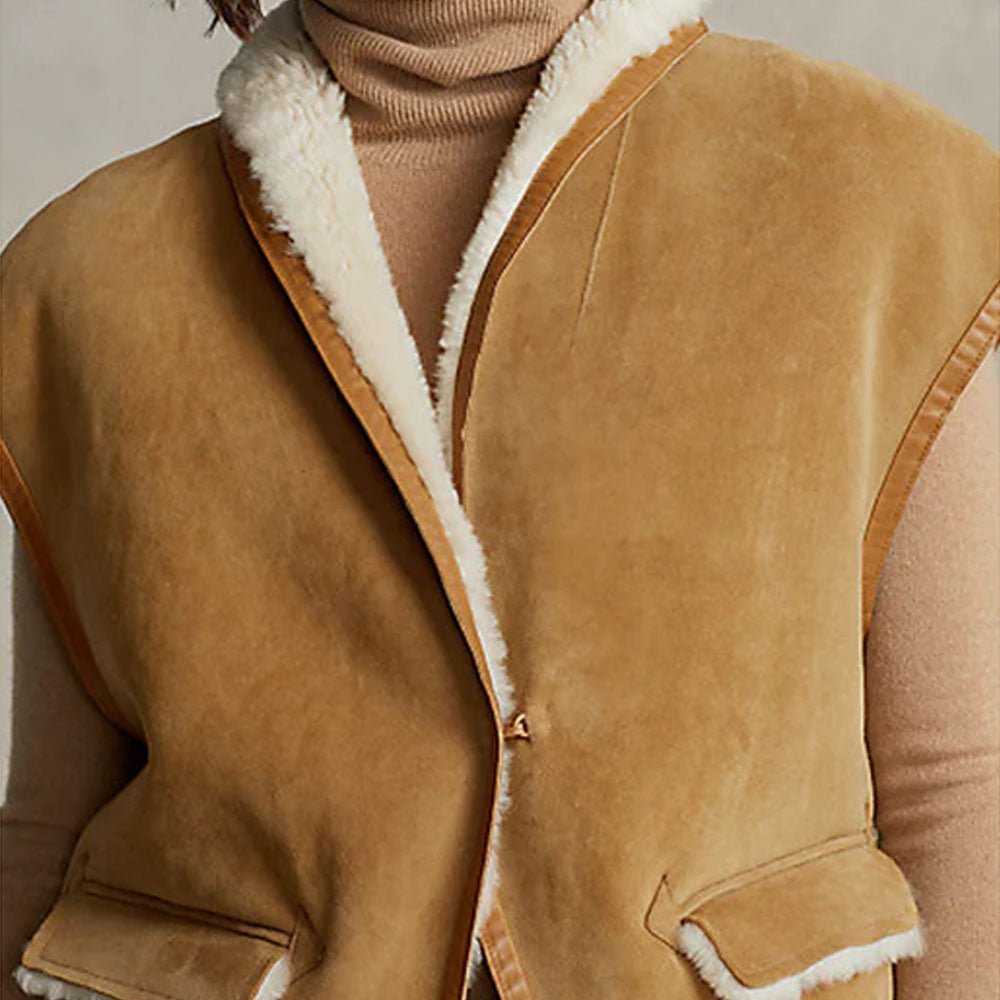 Close-up of the front chest of a brown shearling leather vest, focusing on the detailed stitching and soft faux fur trim.