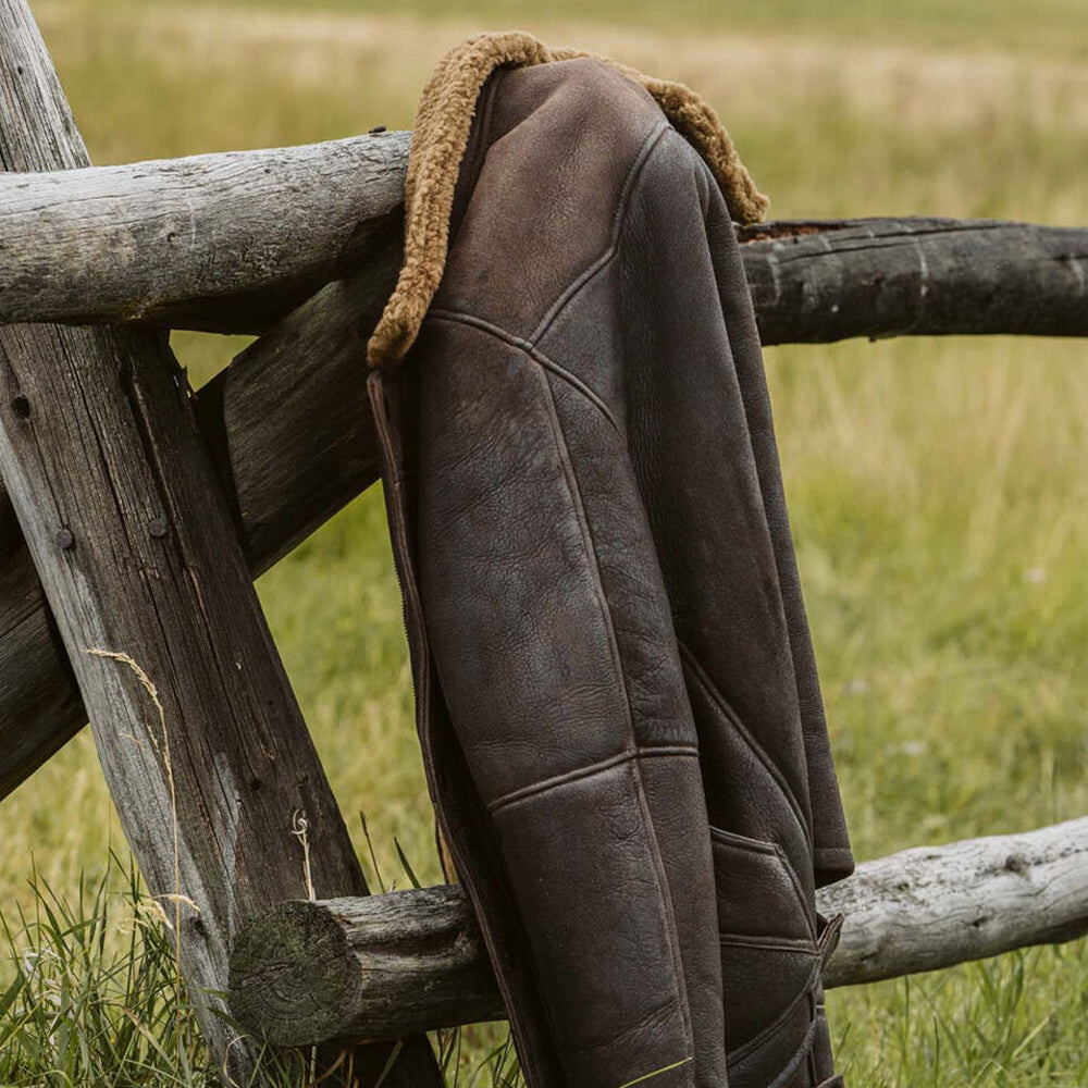 Distressed Brown Leather Sheepskin Jacket Hanging on Wooden Ranch Fence