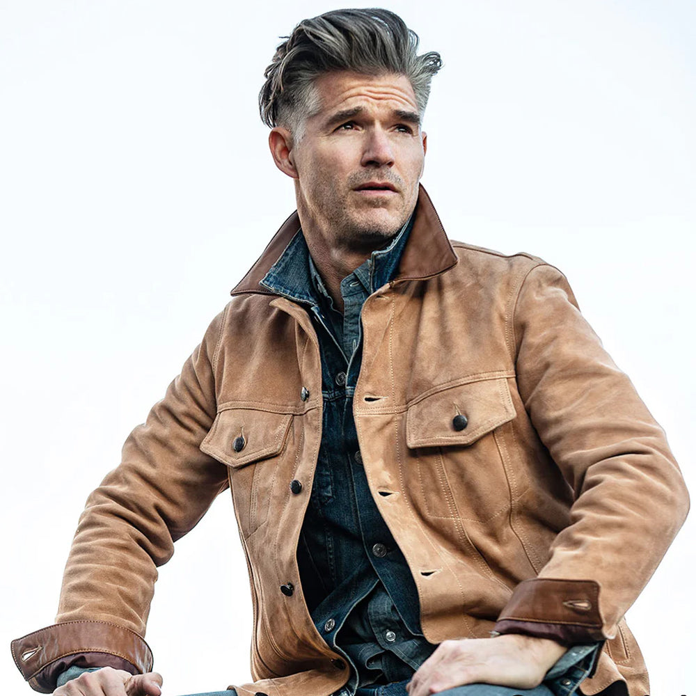 Model sitting down in Men's Brown Suede Leather Trucker Jacket, showcasing its comfort, breathable fit, and timeless design.