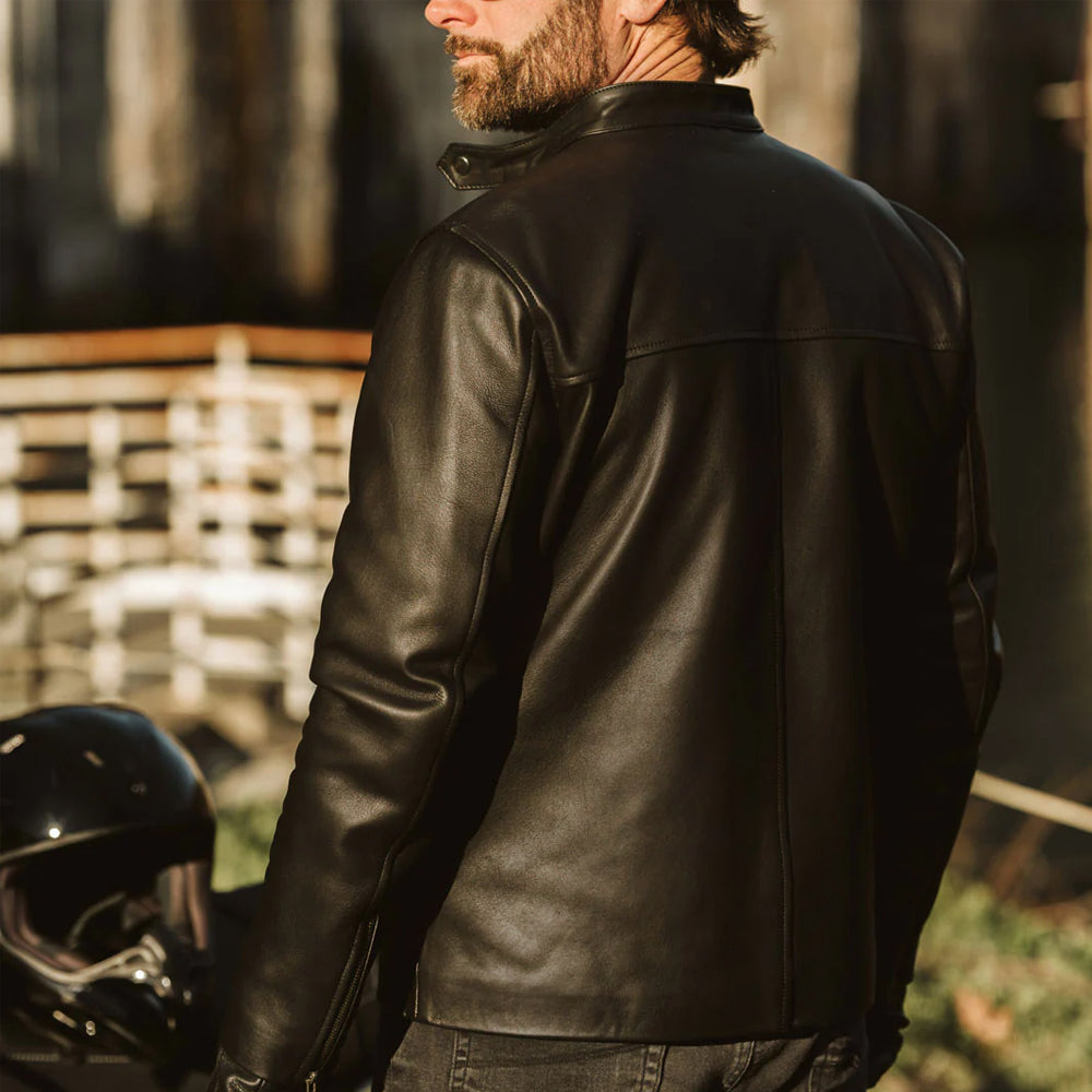 Man standing and showcasing the back view of the vintage black bomber leather jacket.