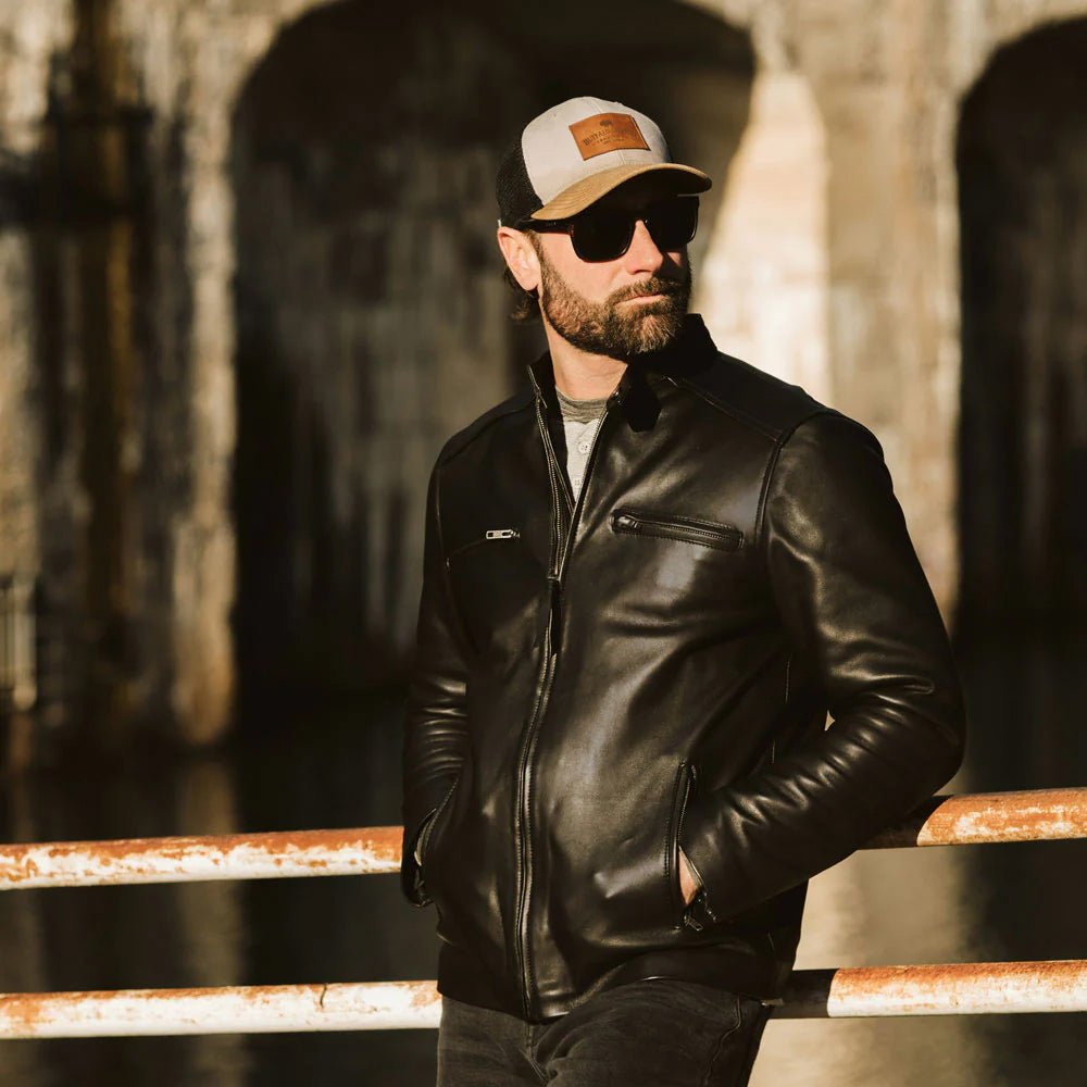 Model wearing a men's black bomber leather jacket with a casual outfit.