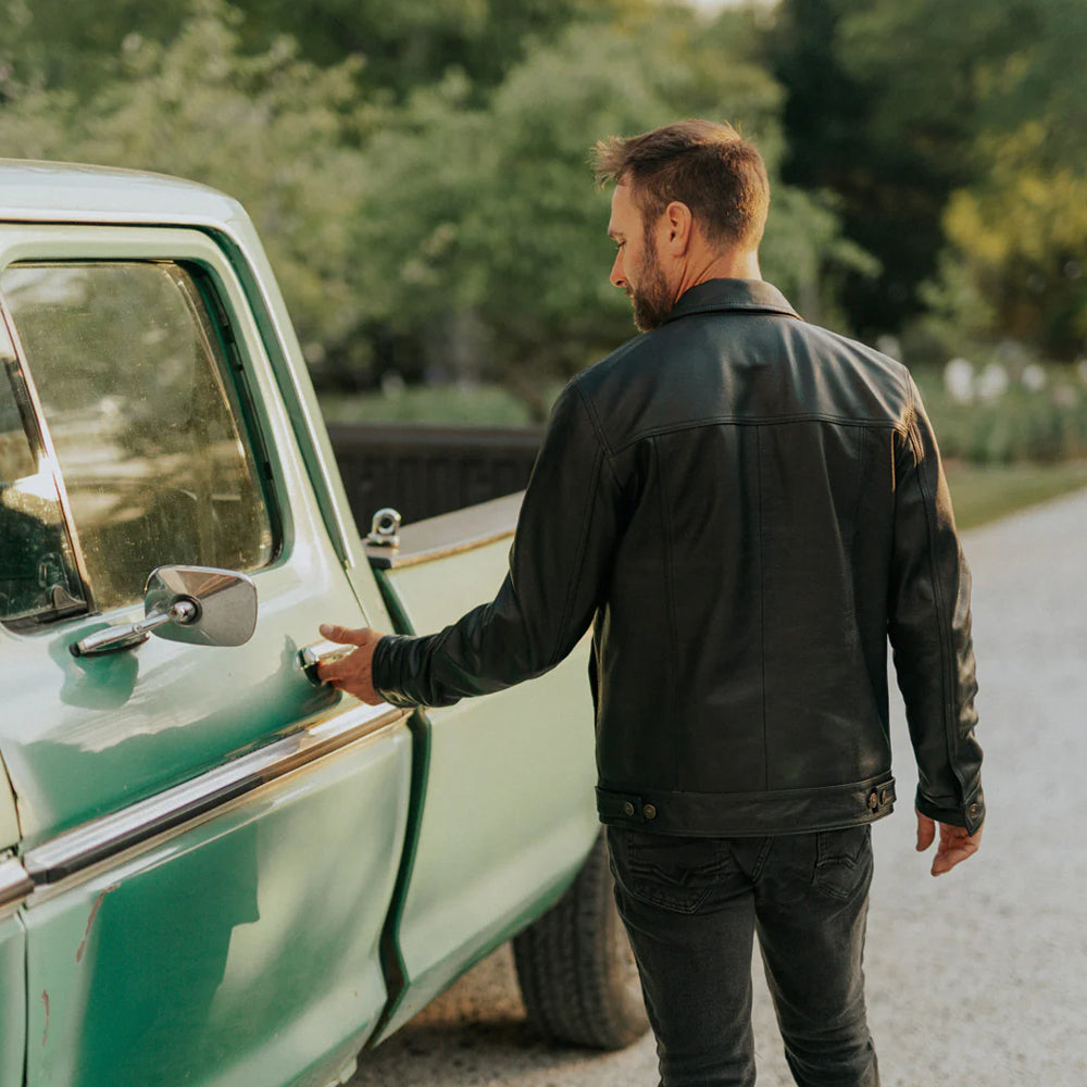 Model wearing Men’s Black Lambskin Leather Trucker Jacket, back view showcasing sleek design and perfect fit.