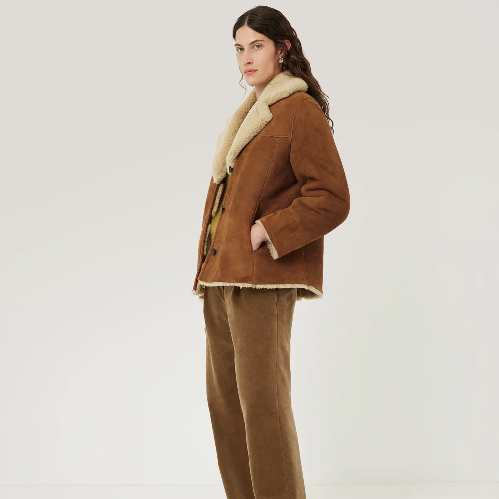 Side view of women's brown shearling suede leather jacket with cuffs.