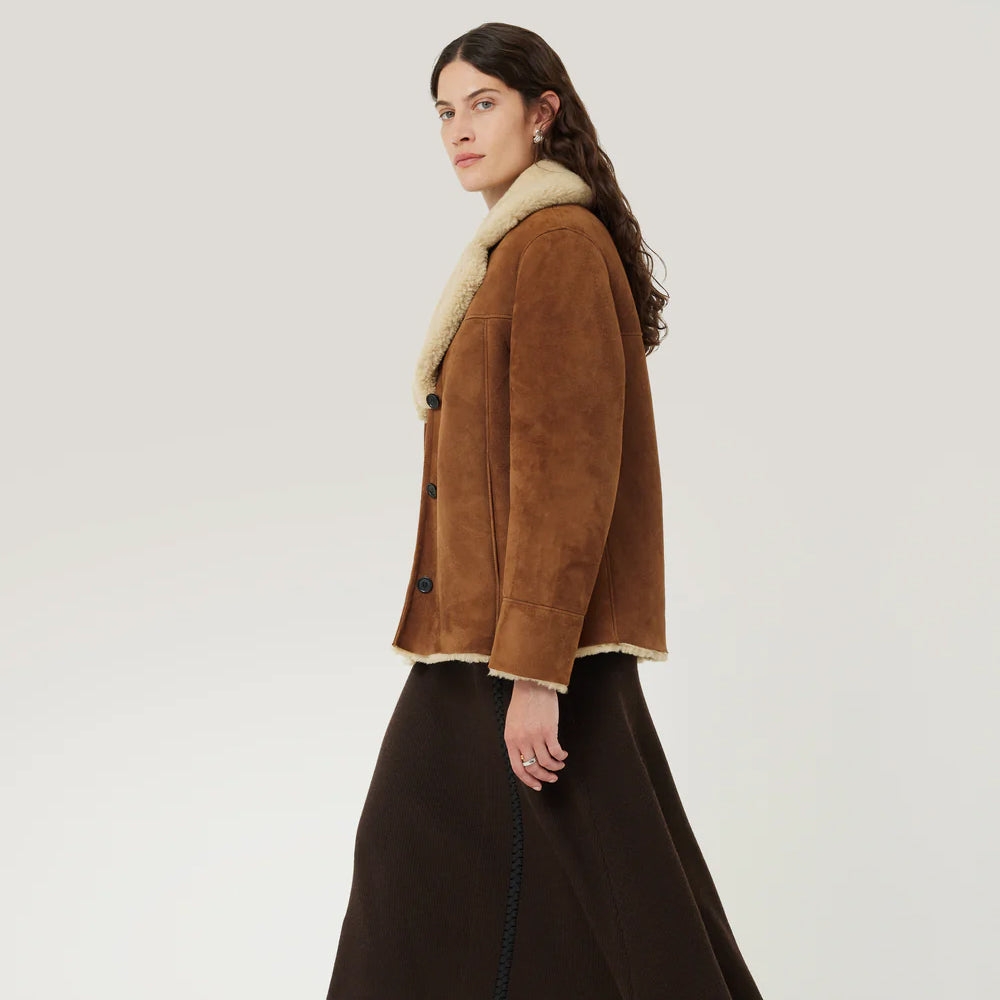 Side view of women's brown shearling suede leather jacket highlighting tailored fit.