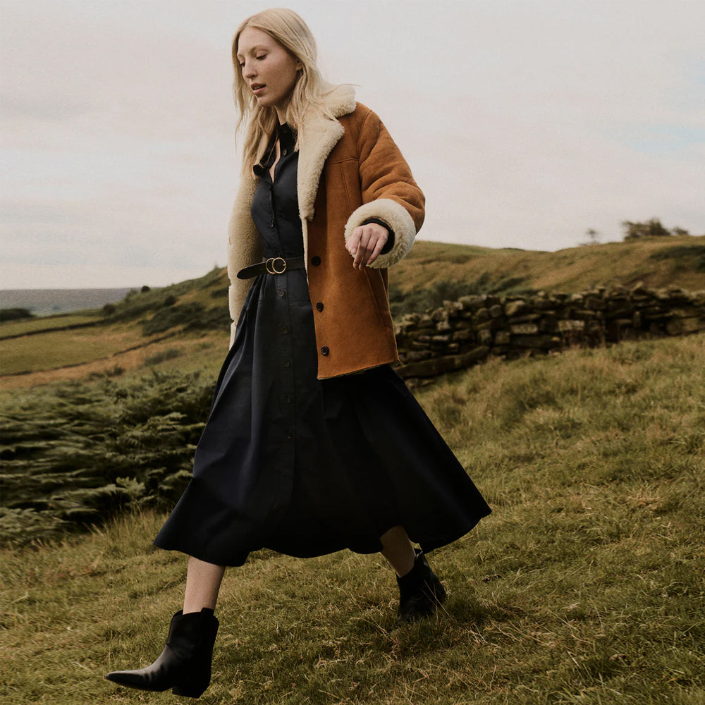 Model wearing a women's brown shearling suede leather jacket in winter.