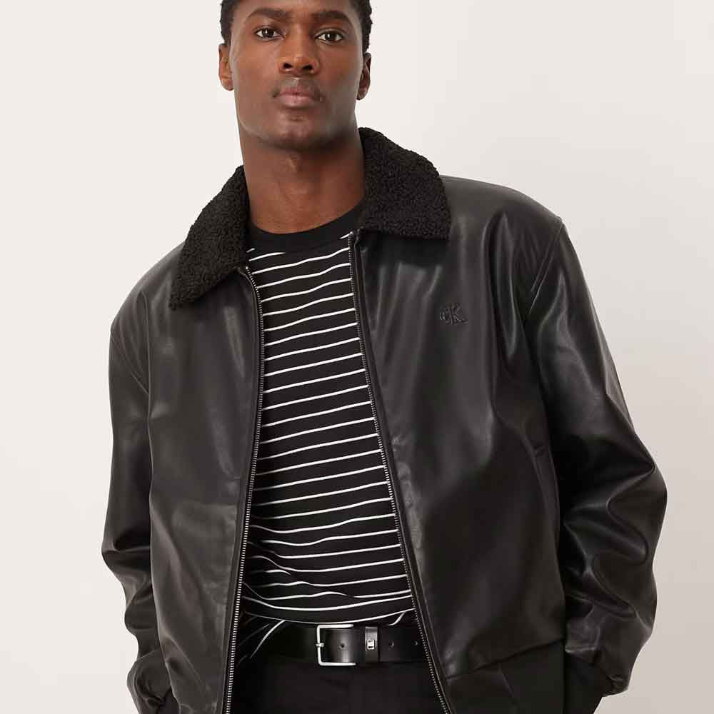 Close front view of smooth black sheepskin aviator bomber with textured sherpa collar and subtle tonal chest mark