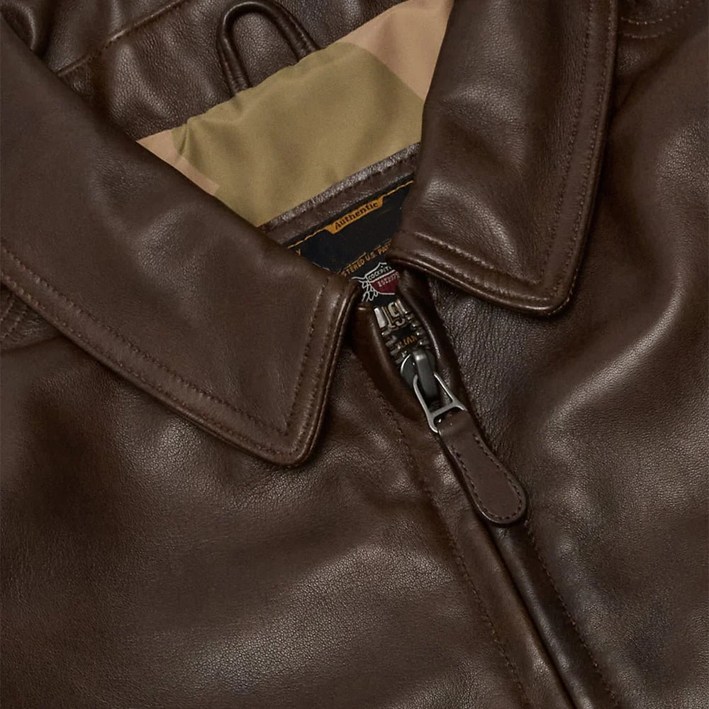 Close detail of smooth brown lambskin, pointed flight collar, tonal stitching, metal zipper and matching leather pull tab.