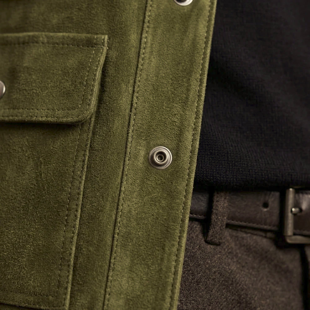 Macro detail of green brushed suede, tonal double-row stitching, silver snap and chest pocket edge construction.