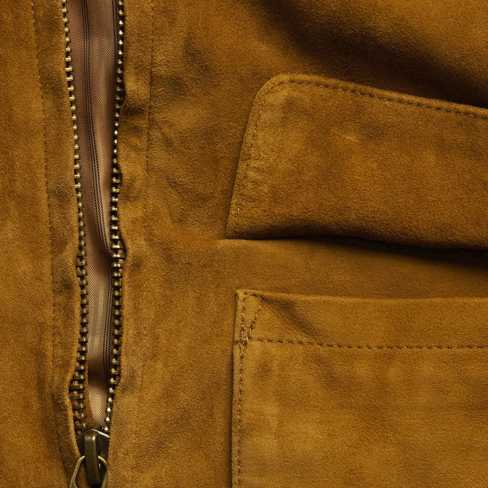 Macro detail of tobacco suede nap, tonal pocket stitching and antique-brass YKK zipper teeth