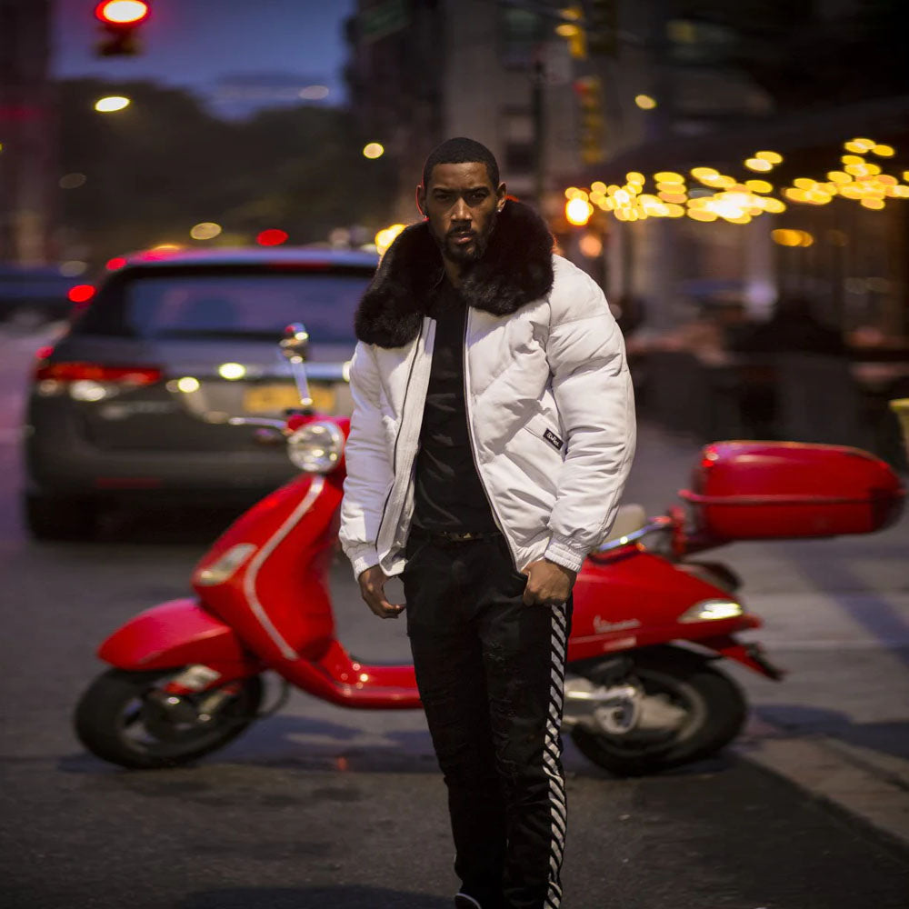 Street-style view of a man posing next to a scooter while wearing the high-contrast white sheepskin leather down puffer coat.
