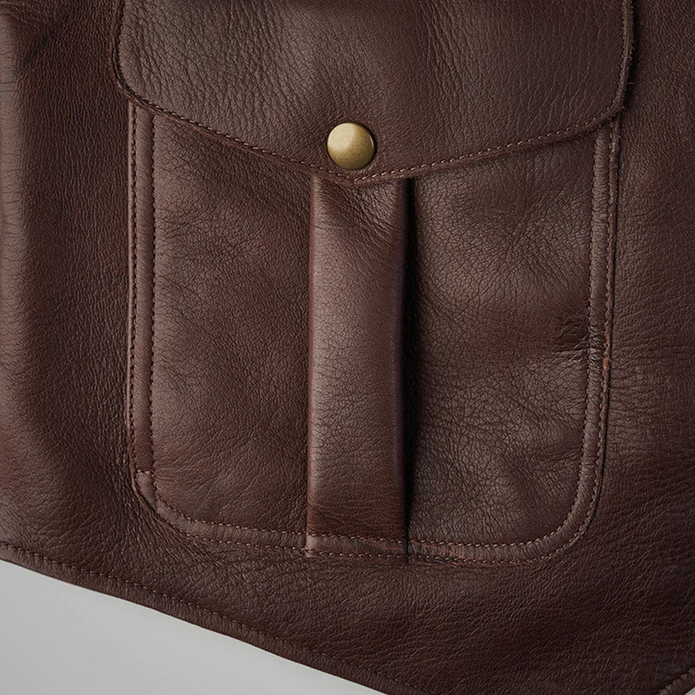 Macro close-up of the lower cargo pocket flap on the brown buckskin leather vest showing the durable perimeter-reinforced stitching.