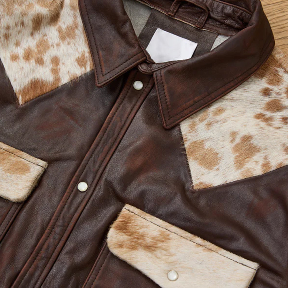Brown leather jacket with cowhide patches on a wooden surface