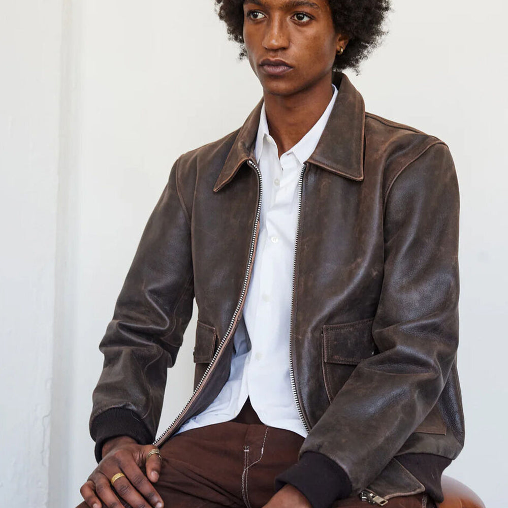 Man sitting while wearing the RAF Vintage A2 Brown Leather Bomber Jacket, looking to the side and showcasing its refined details.
