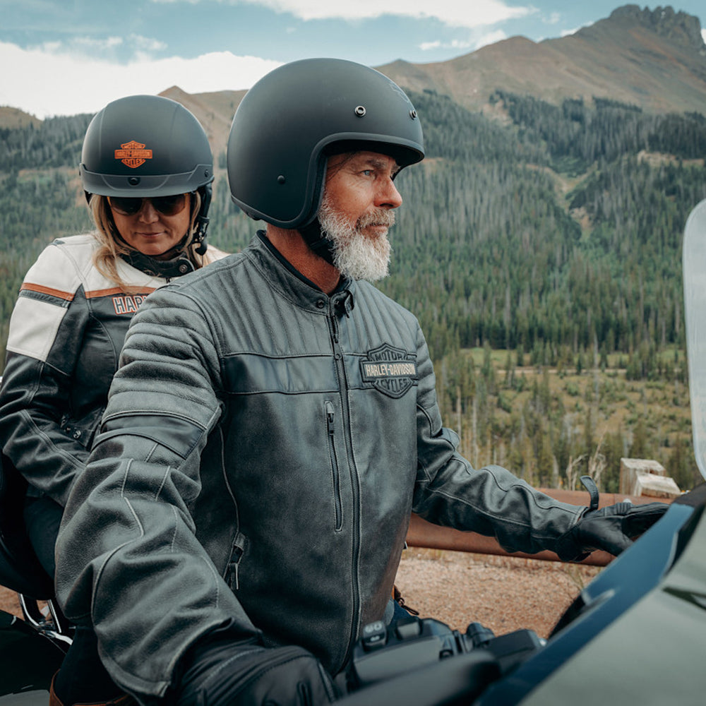 Two people on a motorcycle ride through a mountainous landscape.