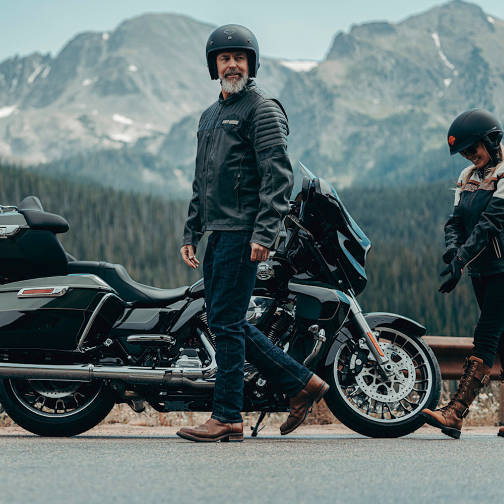 Two people with motorcycles in a mountainous landscape
