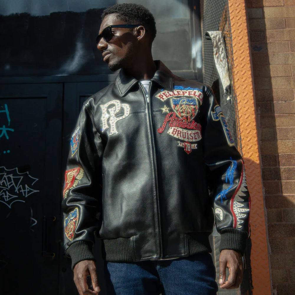 A man wearing a Pelle Pelle black leather jacket with patches in an urban setting