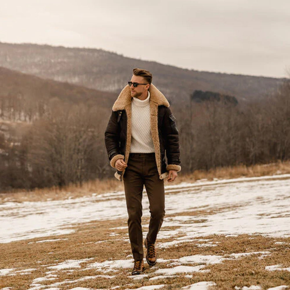 Man standing outside on snowy terrain, wearing the B3 Aviator Sheepskin Jacket and jeans, showing the full-body fit and winter-ready design.