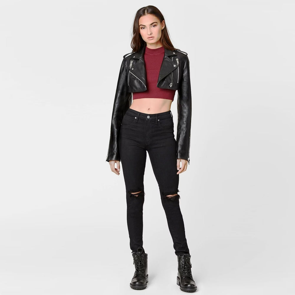 Woman wearing black cropped leather bolero jacket, full body view paired with jeans.