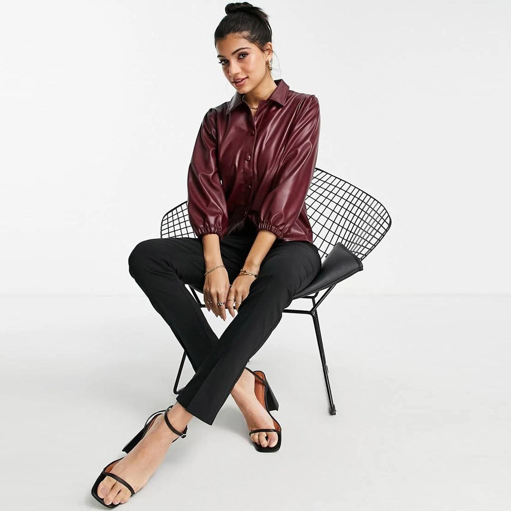 Woman sitting on a chair, showcasing her chic look in a wine-red sheepskin leather balloon sleeve shirt.