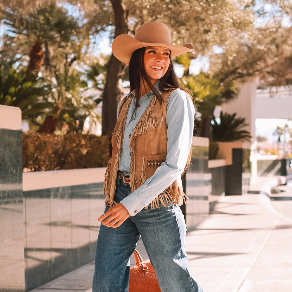 Side view of model wearing a Western suede fringe vest with intricate beadwork and soft suede leather.