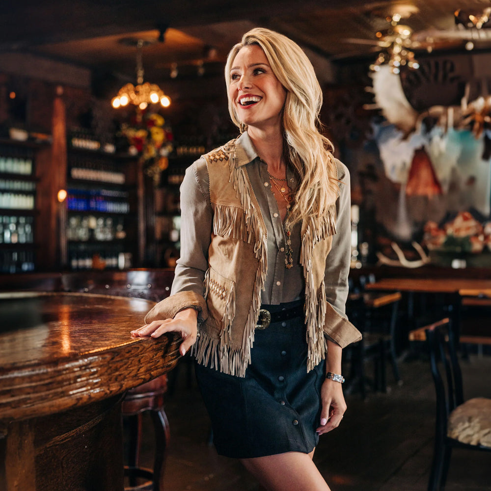 Model wearing a Western fringe vest, looking to the side, highlighting the stylish boho-chic design.