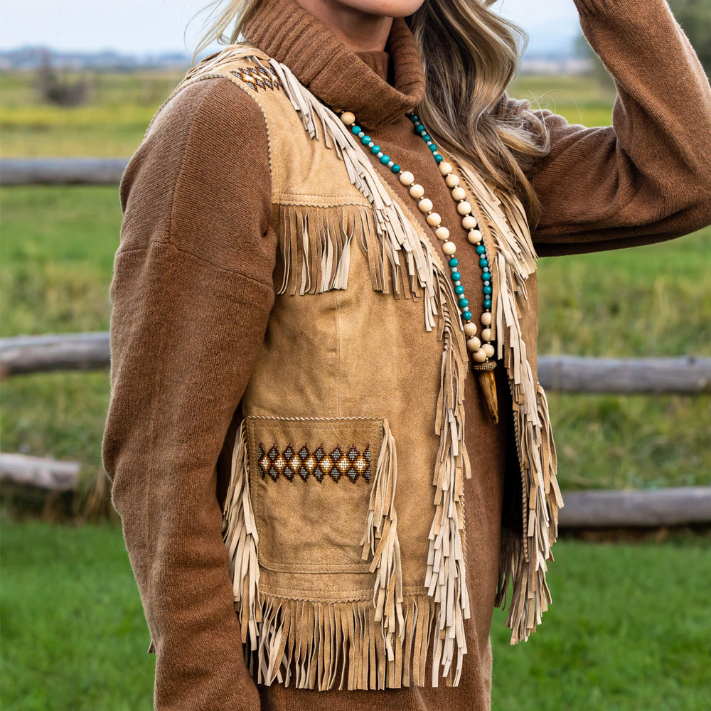 Close-up side view of model wearing a suede fringe vest, highlighting the intricate beadwork and craftsmanship.