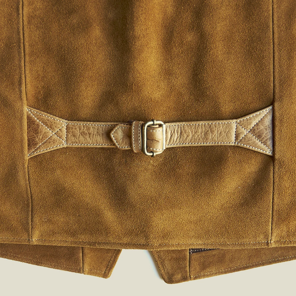 Centered detail of the antique-brass back buckle and top-grain adjustment belt across the tan suede panel