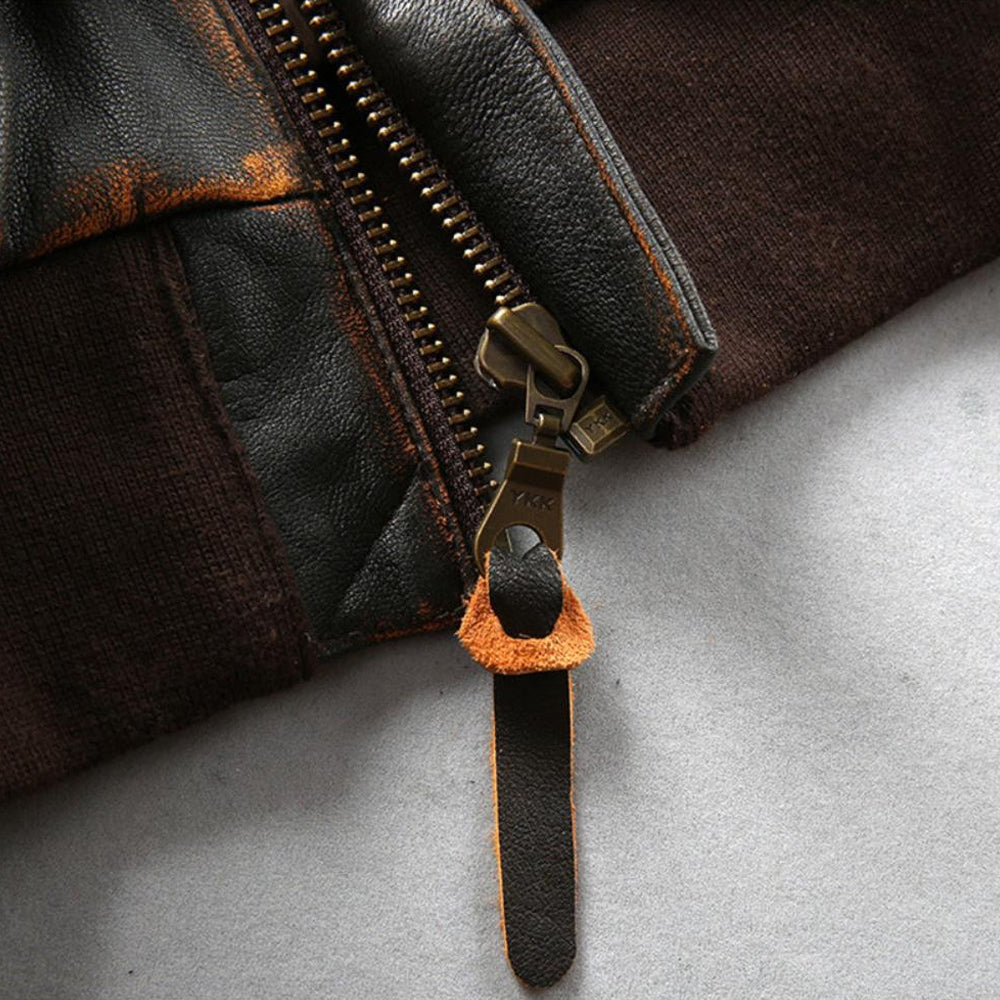 Close-up of antiqued brass YKK front zipper with leather pull tab on brown ribbed hemband.
