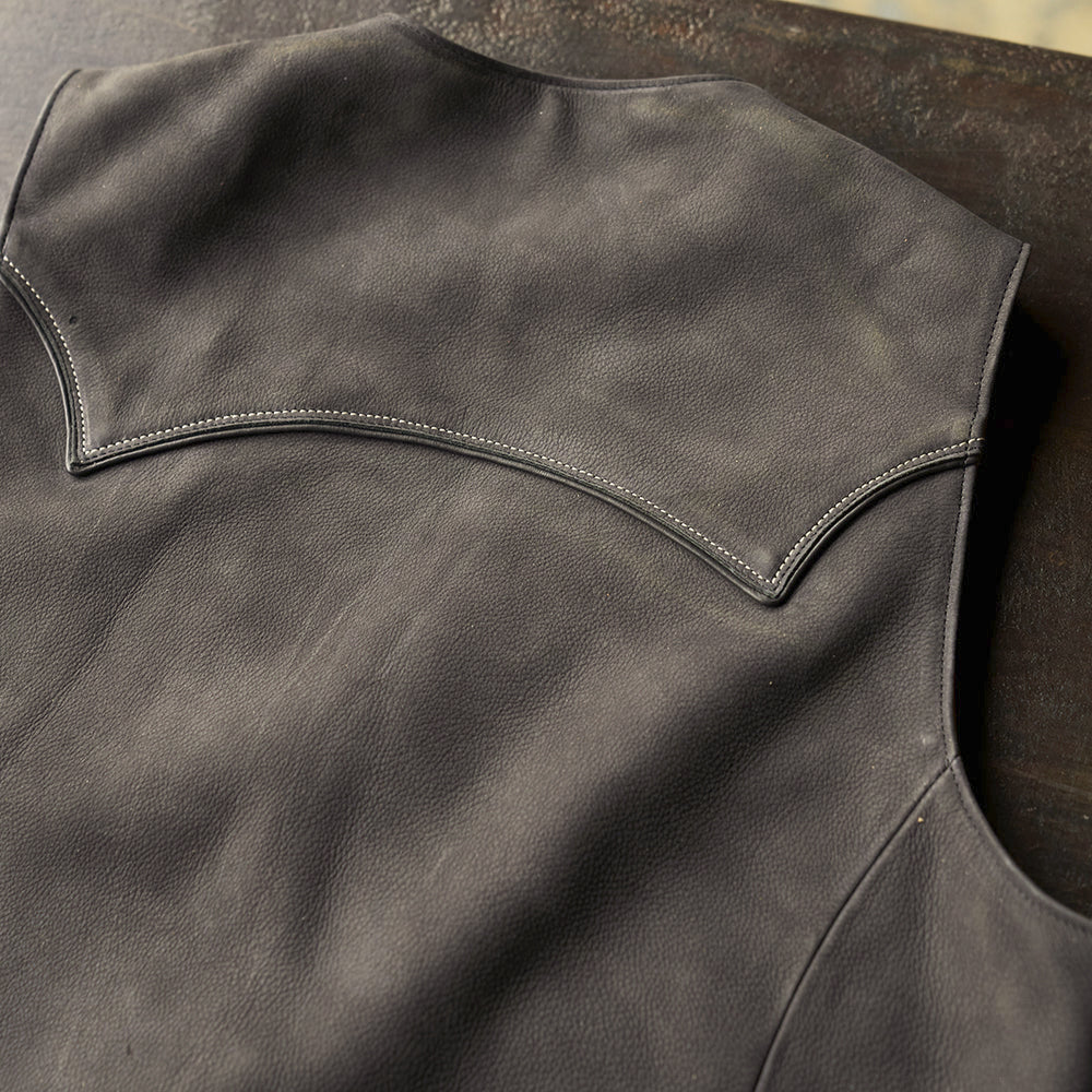Close rear detail of the shallow arched cowboy shoulder yoke outlined with smooth black steerhide piping