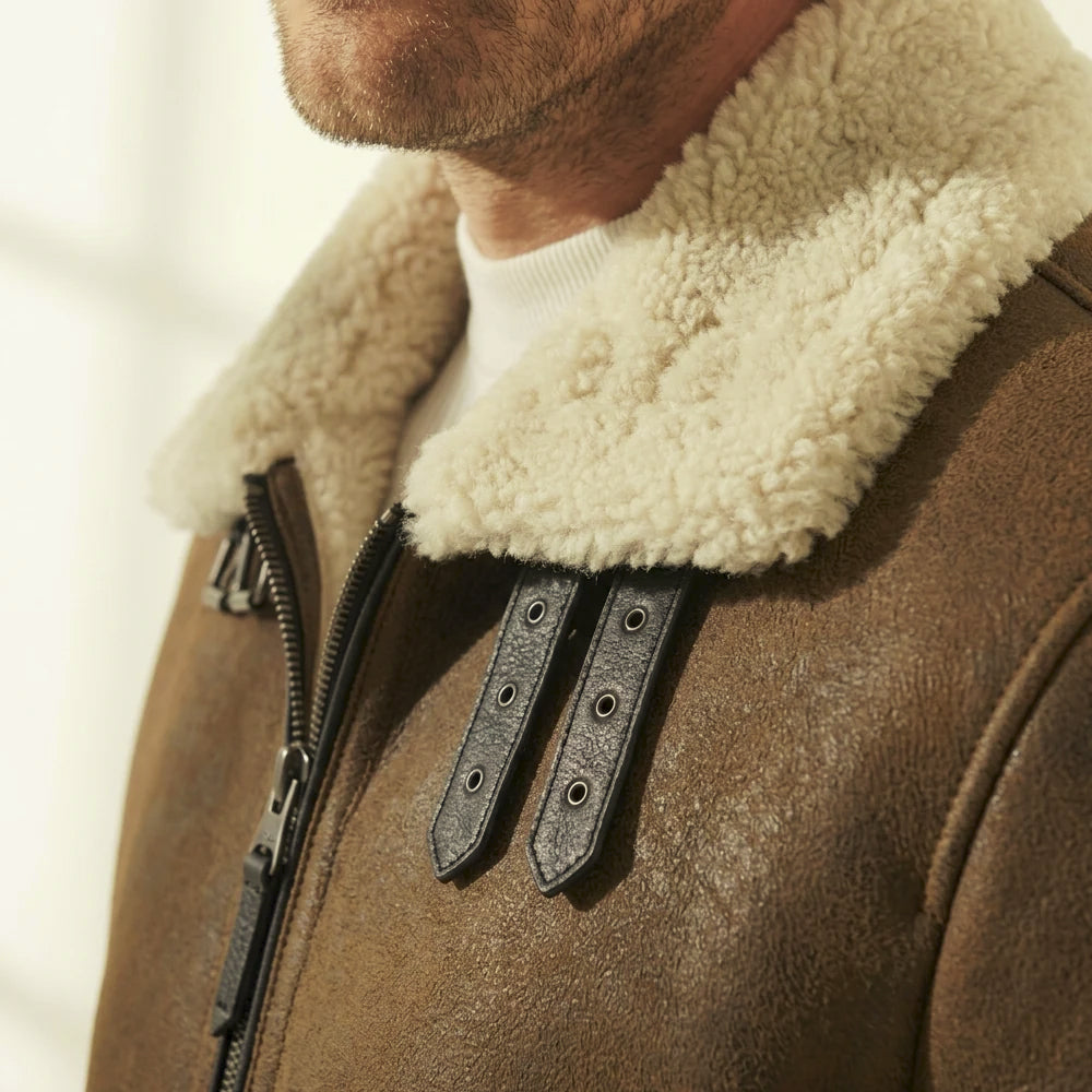 Close-up of the ivory shearling aviator collar with paired leather throat tabs, metal eyelets and buckle hardware