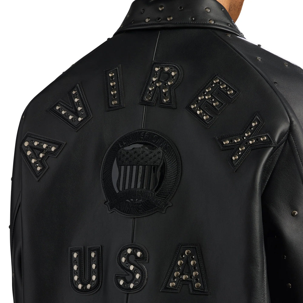 Close-up of raised AVIREX USA leather appliqués filled with dark metal studs around a tonal circular crest