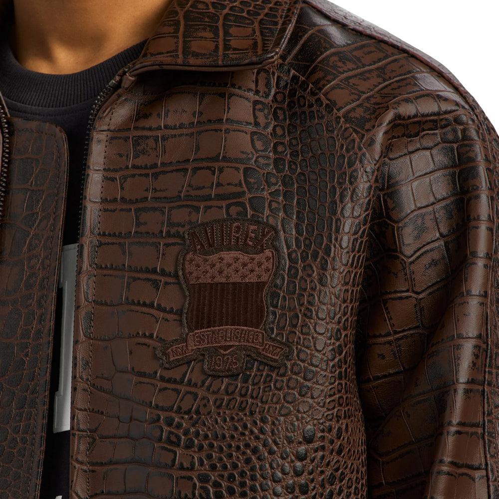 Close-up of tonal Avirex 1975 chest crest on raised brown crocodile-effect leather