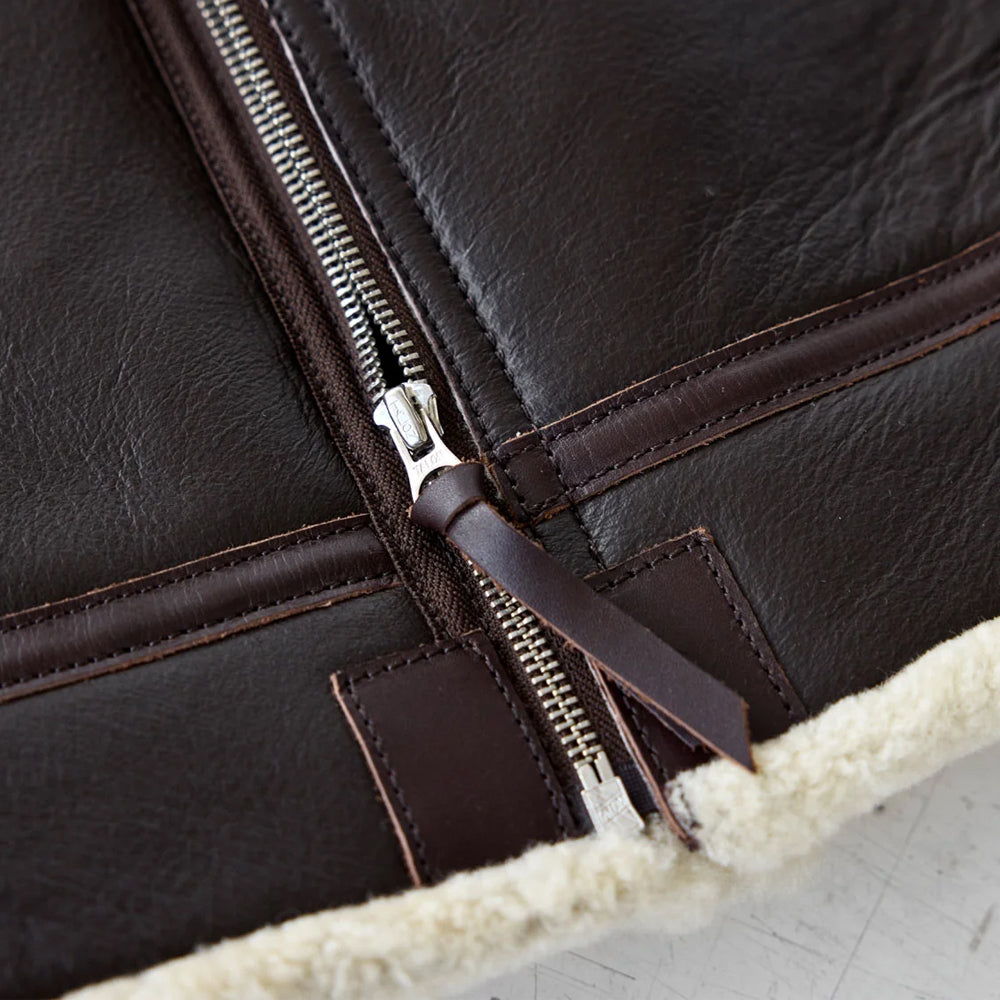Close-up of YKK metal zipper and contrast stitching on dark brown B-3 aviator jacket