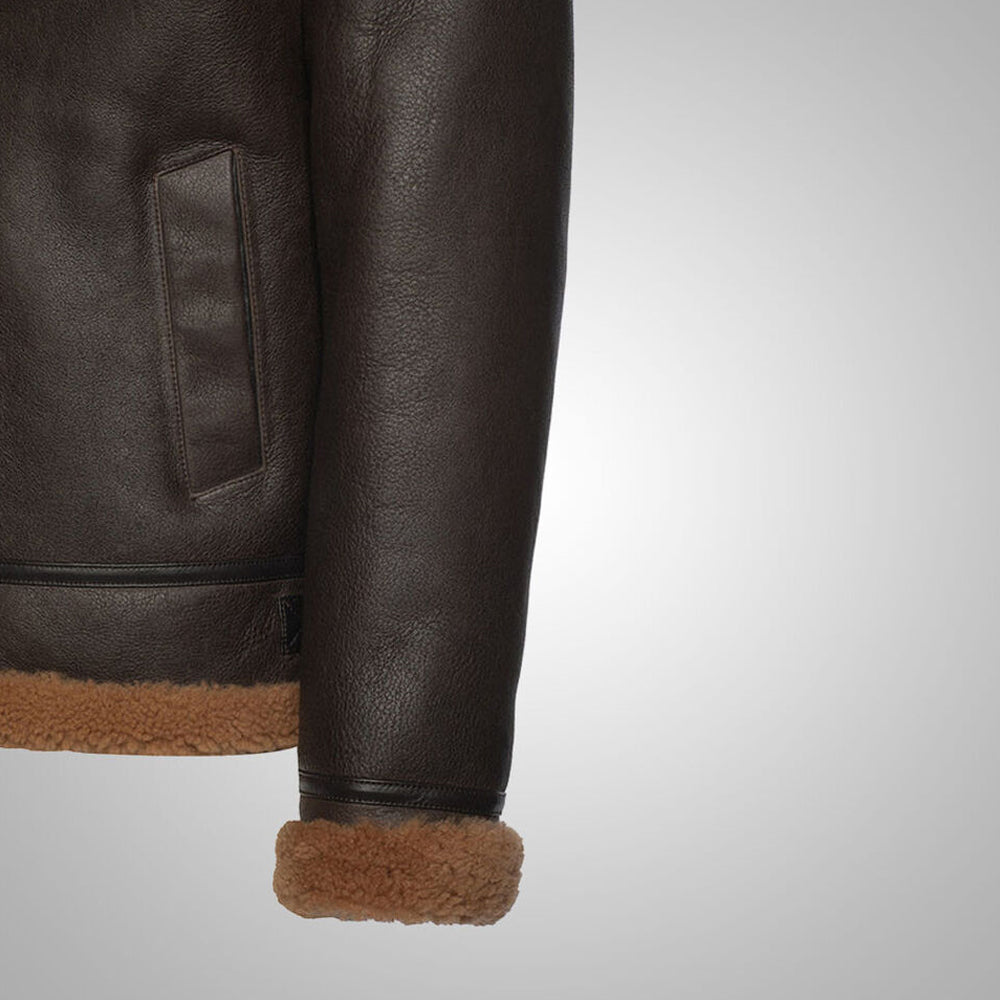 Detail view of slanted waist welt pocket and turned-up tan shearling wrist cuff on brown B3 flight jacket