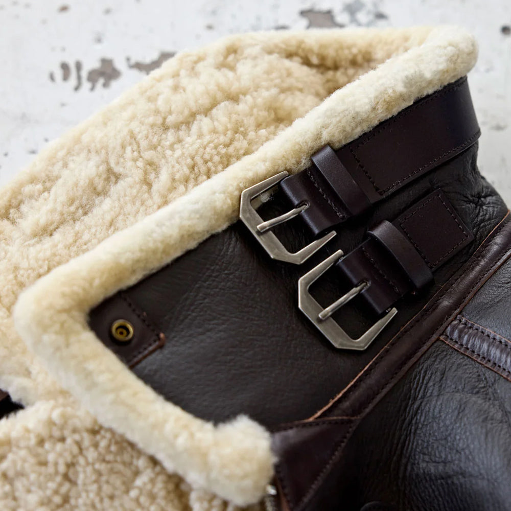 Close-up of cream shearling aviator collar with two dark brown leather buckle straps