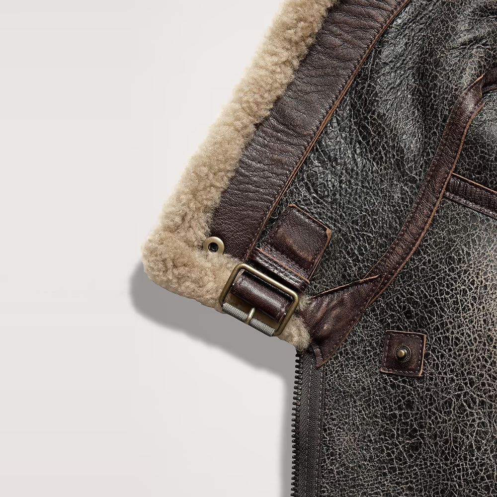 Close-up of crackled leather, cream shearling trim and antique brass waist buckle on a B-3 jacket