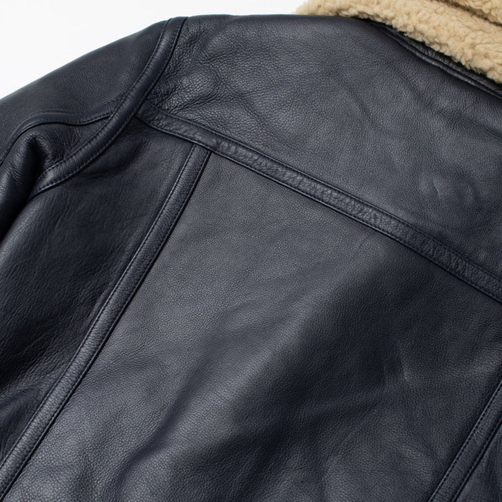 Detailed view of reinforced back yoke seam stitching and vertical piping on men's black leather B-3 coat
