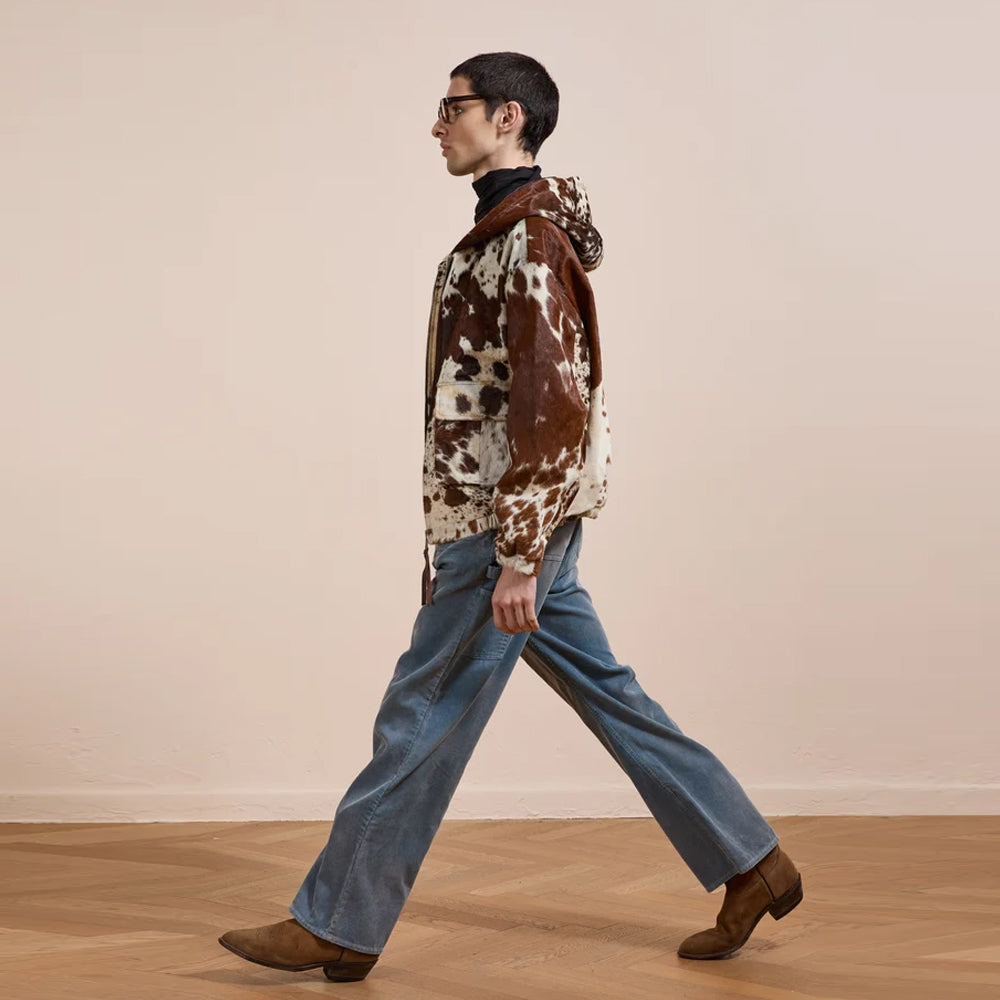 Side profile of the relaxed brown and cream cowhide workwear jacket showing its hip length and gathered waist