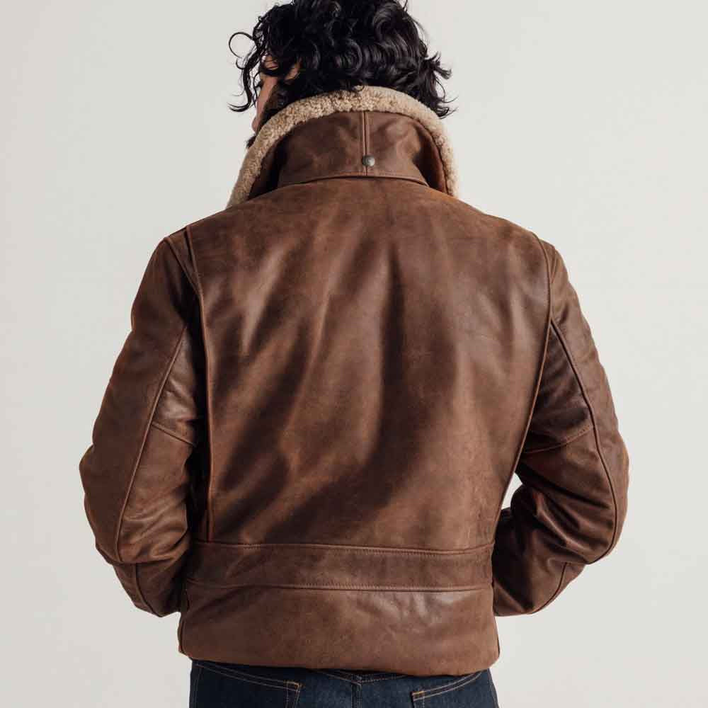 Rear model view of brown G-1-inspired bomber showing broad seamless leather panel, collar snap tab and lower leather band