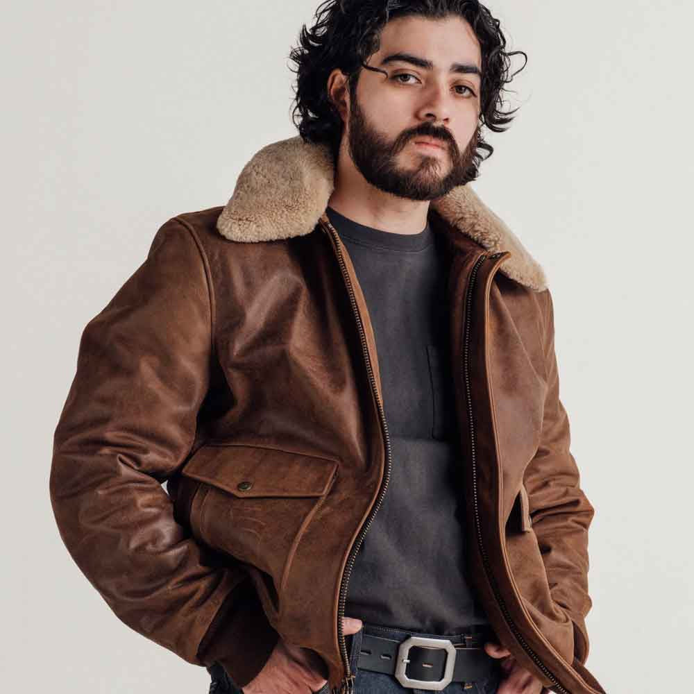 Three-quarter view of men’s brown leather bomber showing detachable genuine shearling collar and dual-entry snap-flap pocket