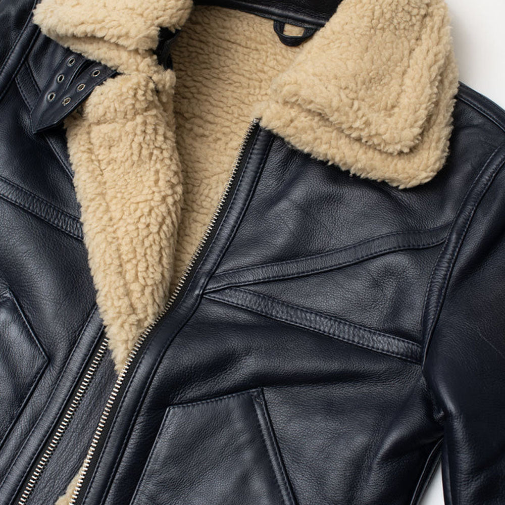 Close-up view of chevron seam stitching and dual leather throat latch buckles on a black shearling coat