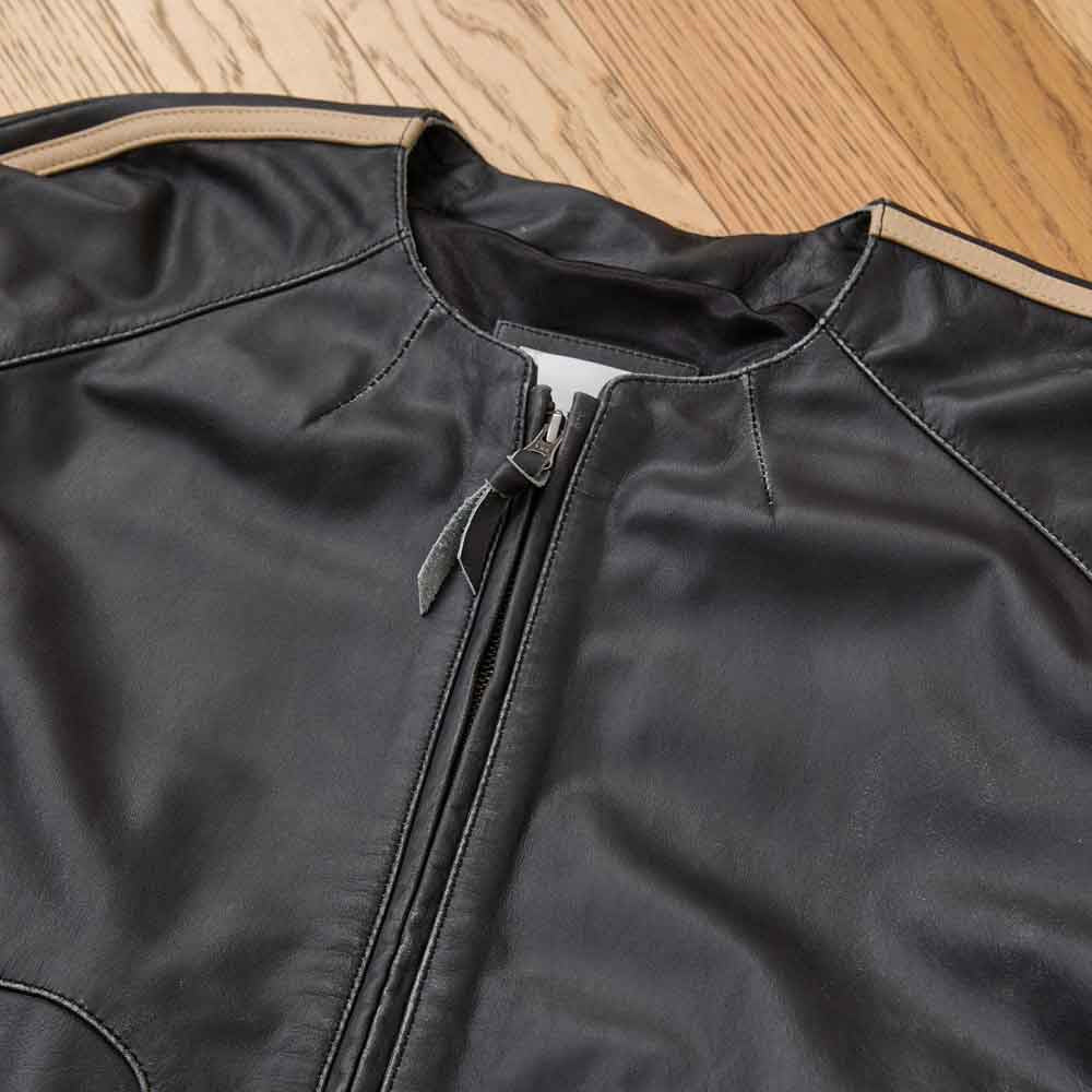Close-up of collarless round neckline and antique-brass YKK front zipper on vintage black leather track jacket