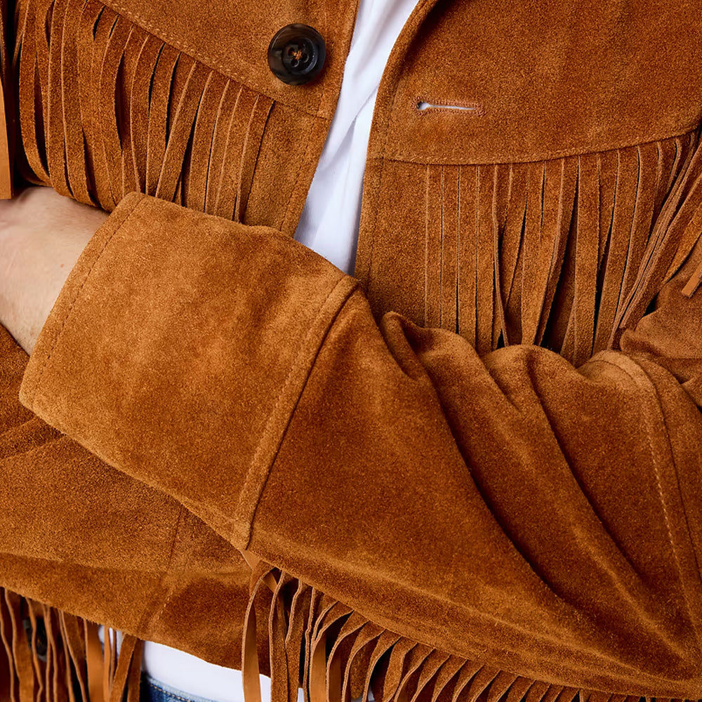 Close-up of cowboy suede jacket showing cognac nap, straight open cuff, dark button and narrow-cut chest fringe.