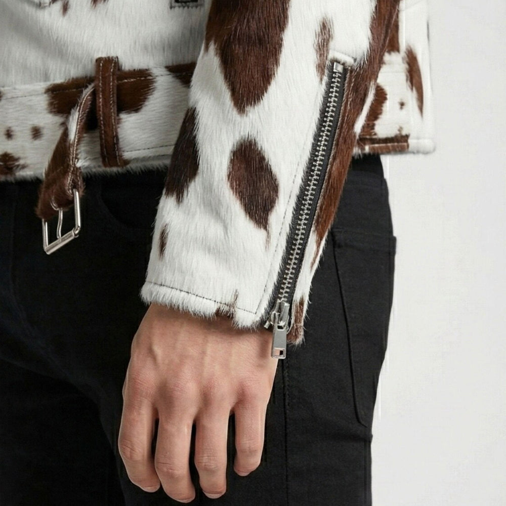 Close-up of silver-tone cuff zipper and fixed half belt on a spotted cowhide biker jacket