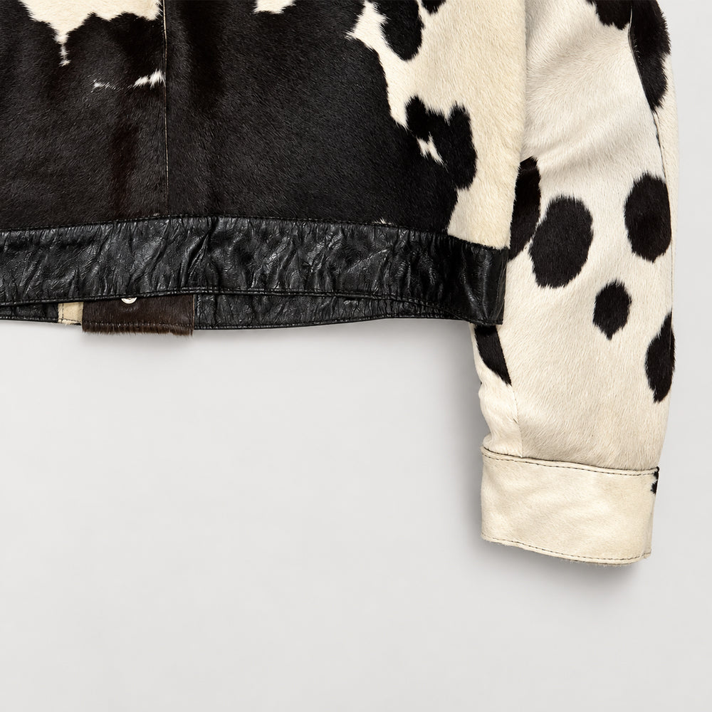 Close-up of natural cowhide snap cuff and espresso lambskin hem on a men’s Western jacket